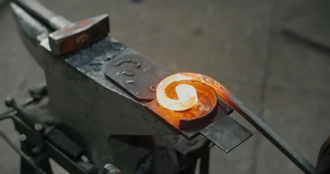 Blacksmith bends a red-hot metal rod on an anvil into a spiral, decorative Stock Footage 151893775