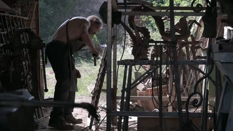 Blacksmith cleaning slag from a grating after welding. Stock Footage 247330300