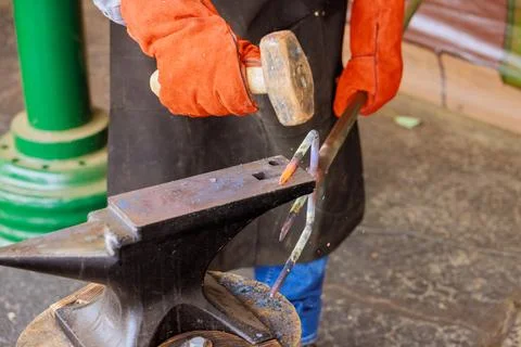 Blacksmith crafts metal tools in workshop using hammer anvil during daytime Stock Photos