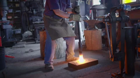 Blacksmith creates sparks while pounding metal on floor HD Stock Footage 49371109