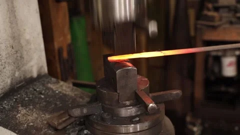 Blacksmith drawing out hot iron under a power hammer Stock Footage 153473833