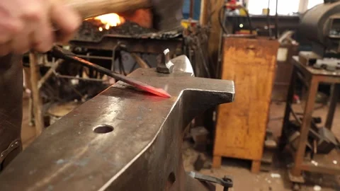 Blacksmith Drawing a point on hot iron bar Stock Footage 153495149