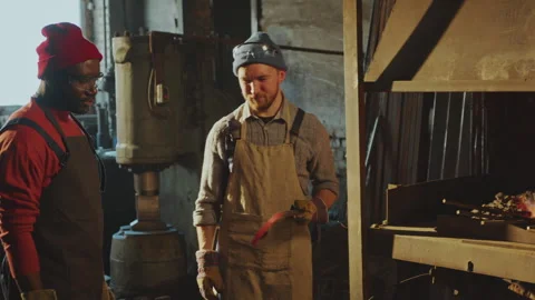 Blacksmith Explaining How to Shape Red-Hot Iron to Colleague in Workshop Stock Footage 274388526