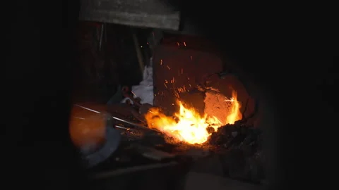 A blacksmith on fire heats the metal for forging the product Stock Footage 146934343