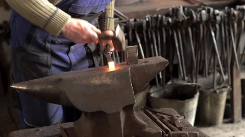 Blacksmith forges hinge on a anvil. Hammering hot red steel Stock Footage 180990401