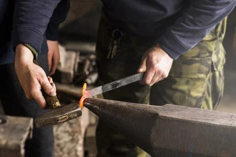 Blacksmith forges hinge on a anvil. Hammering hot red steel Foto stock