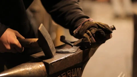 Blacksmith forges a horseshoe in a craft workshop. Horseshoe for good luck Stock Footage 98158882