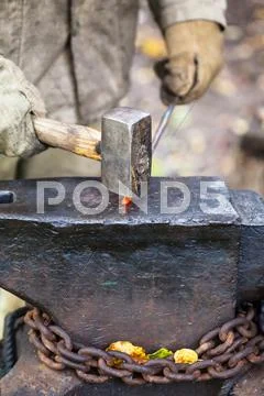 Blacksmith forges hot iron rod with sledgehammer Stock Photos