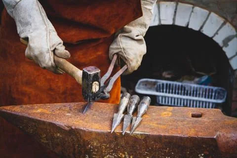 A blacksmith forges iron. Blacksmith's workshop. Blacksmith's anvil and hamme Stock Photos