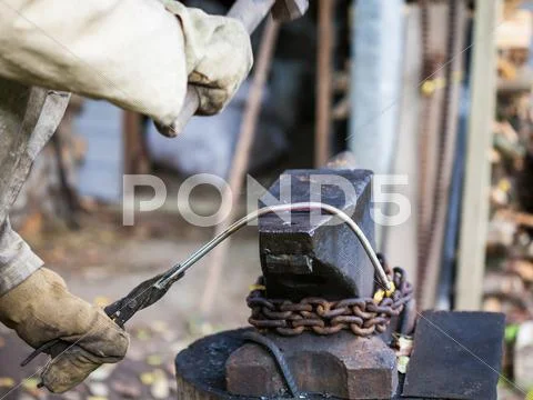 Blacksmith forges iron rod on an anvil Stock Photos