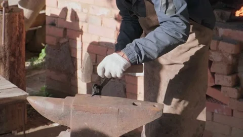 Blacksmith forges a nail with a hammer on an anvil. The blacksmith in the pro Stock Footage 209143161