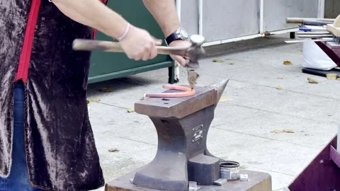 Blacksmith forging heated metal on anvil outdoors Stock Footage 291733358
