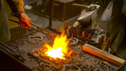 Blacksmith forging iron heart in workshop fire Stockbeeldmateriaal 334626189