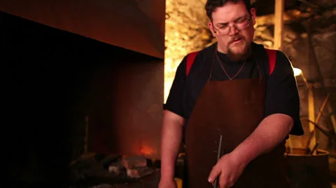Blacksmith forging iron, stops, looks at work, medium shot Stock Footage 39017124