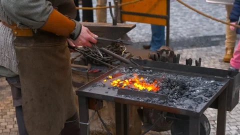 Blacksmith forging metal at an outdoor forge Stock Footage 333238035