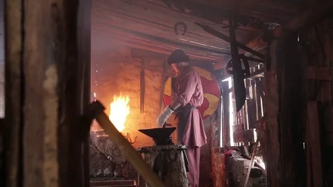 Blacksmith forging the molten metal on the anvil in smithy Stockbeeldmateriaal 70825818