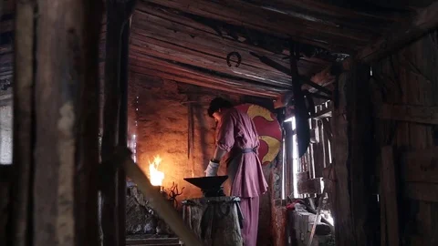 Blacksmith forging the molten metal on the anvil in smithy 库存影片 70825823