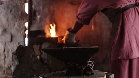 Blacksmith forging the molten metal on the anvil in smithy Видео 70825857