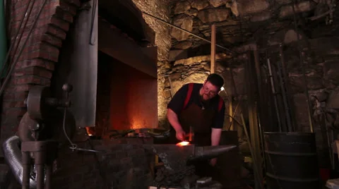 Blacksmith forging red hot iron in historic shop, wide shot Stock Footage 39022892
