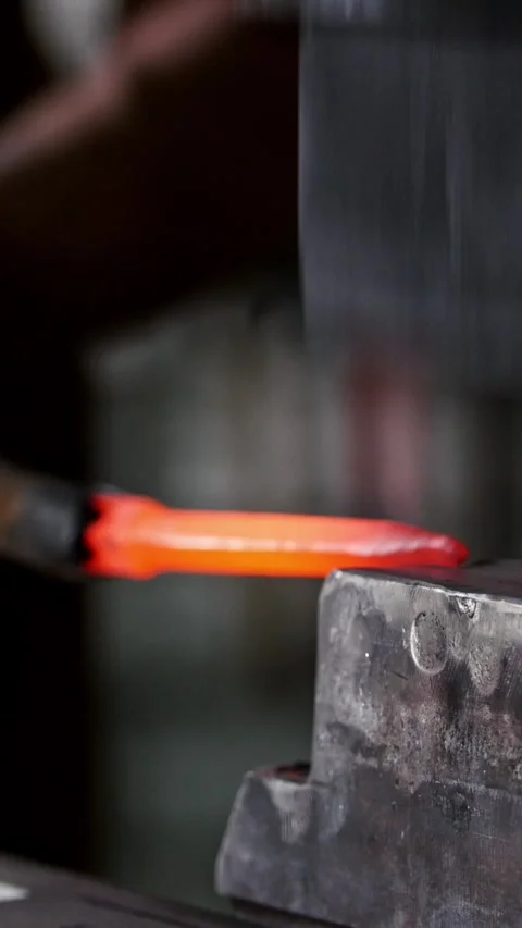 Blacksmith forging red hot iron on anvil - automatic hammering Stock Footage 332614461