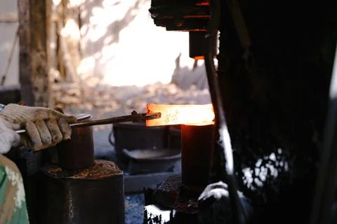 The blacksmith is forging very hot iron to make various tools. Stock Photos