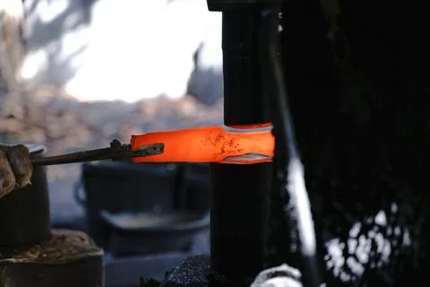 The blacksmith is forging very hot iron to make various tools. Stock Photos