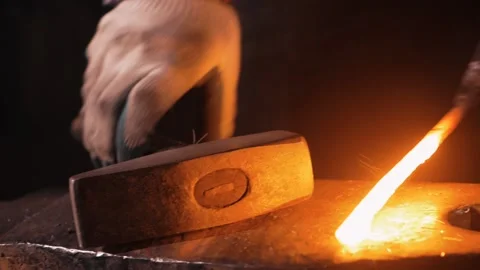 A blacksmith forms a workpiece on an anvil with a hammer. sparks Stock Footage 133078132
