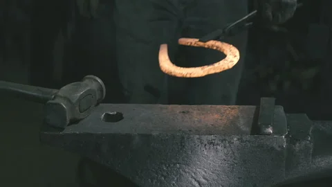 The blacksmith gets a horseshoe from the fire and works on it Stock Footage 109600358