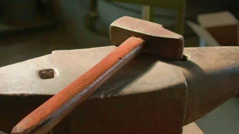 Blacksmith hammer anvil warm light beam handheld shot Stock Footage 341340875