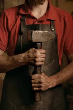 Blacksmith with hammer in hands in workshop Stock Photos