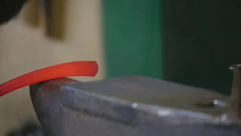 Blacksmith hammering the end of an Iron bar into a hook Stock Footage 78903457
