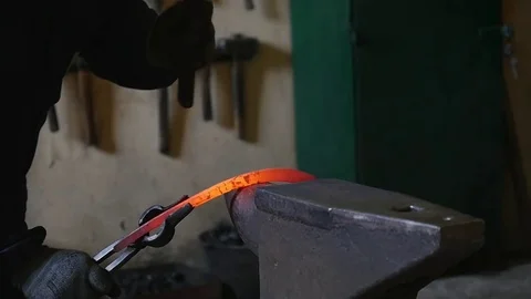 Blacksmith hammering the end of an Iron bar into a hook Stock Footage 78904724