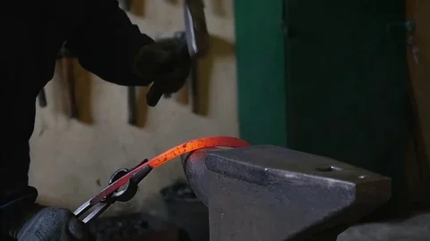 Blacksmith hammering the end of an Iron bar into a hook Stock Footage 78904775
