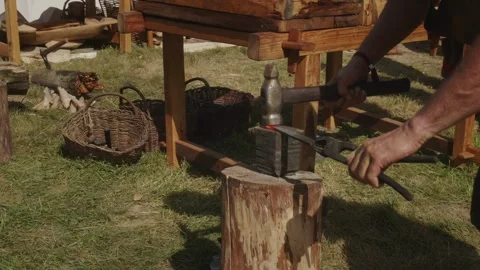 Blacksmith hammering hot iron on anvil with large hammer Stock Footage 319947386