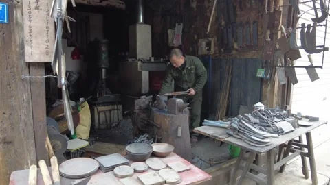 Blacksmith hammering hot iron to make farm tools in traditional smithy Stock Footage 337522624