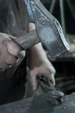 Blacksmith hammering iron on anvil at workshop Stock Photos