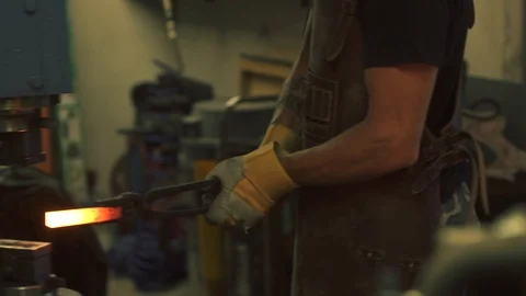 Blacksmith hammering a metal object with a power hammer Stock Footage 128597061