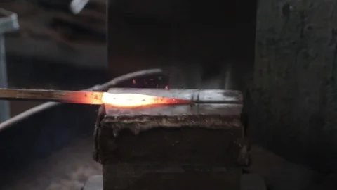Blacksmith is hammering red hot iron on anvil. Close-up. Video stock 80741854
