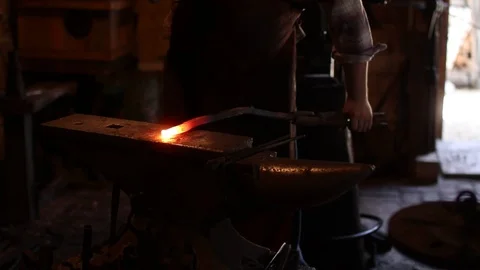 Blacksmith hammering a red hot piece of metal on an anvil Stock Footage 92867843