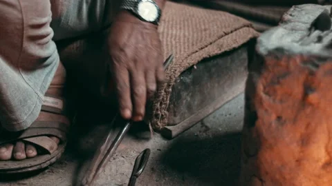 Blacksmith hand using metal tongs to remove steel piece from hot furnace fire Stock Footage 133185953