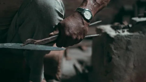 Blacksmith hand using metal tongs places steel piece into hot furnace fire Stock Footage 135257744