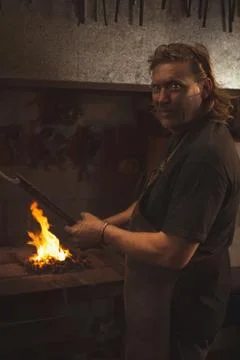 Blacksmith heating a piece of metal in workshop Stock Photos