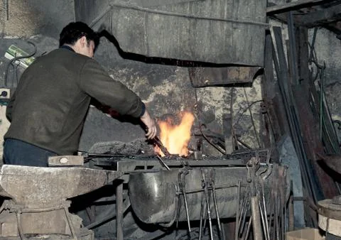 Blacksmith heats iron in the fire Photos