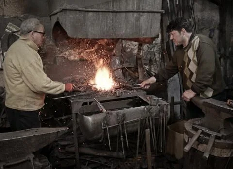 Blacksmith heats iron in the fire Photos