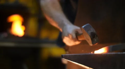 Blacksmith hit with Hammer Hot Metal in a Workshop Behind is a Forge Stock Footage 55449399