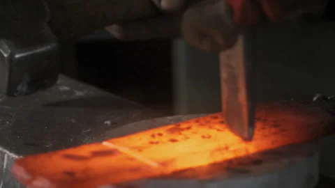 Blacksmith hitting a chisel into smelted hot metal Stock Footage 275509049