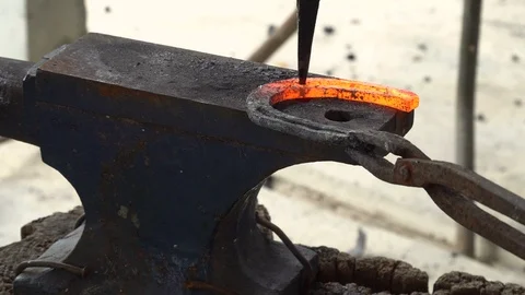The blacksmith kicks a horseshoe close up Stock Footage 100434645
