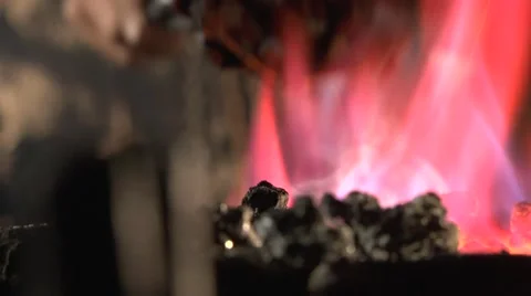 Blacksmith kindles a torch in fire, and gazes at his handiwork. Stock Footage 49400150