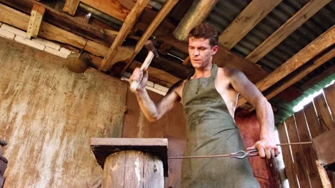 The blacksmith knocks with a hammer, creates items from wrought iron. Stock Footage 139850664