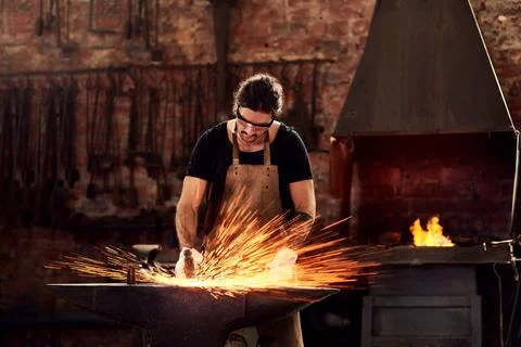 Blacksmith, man and metal workshop and sparks, manual forge working on hot steel Stock Photos